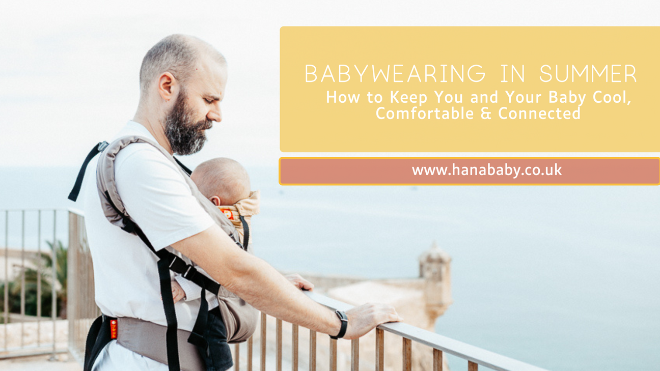 A Daddy on holiday stands against railings over looking the sea from Alicante Castle. He is wearing his three month old baby in the Hana Baby Expand, which is grey and yellow