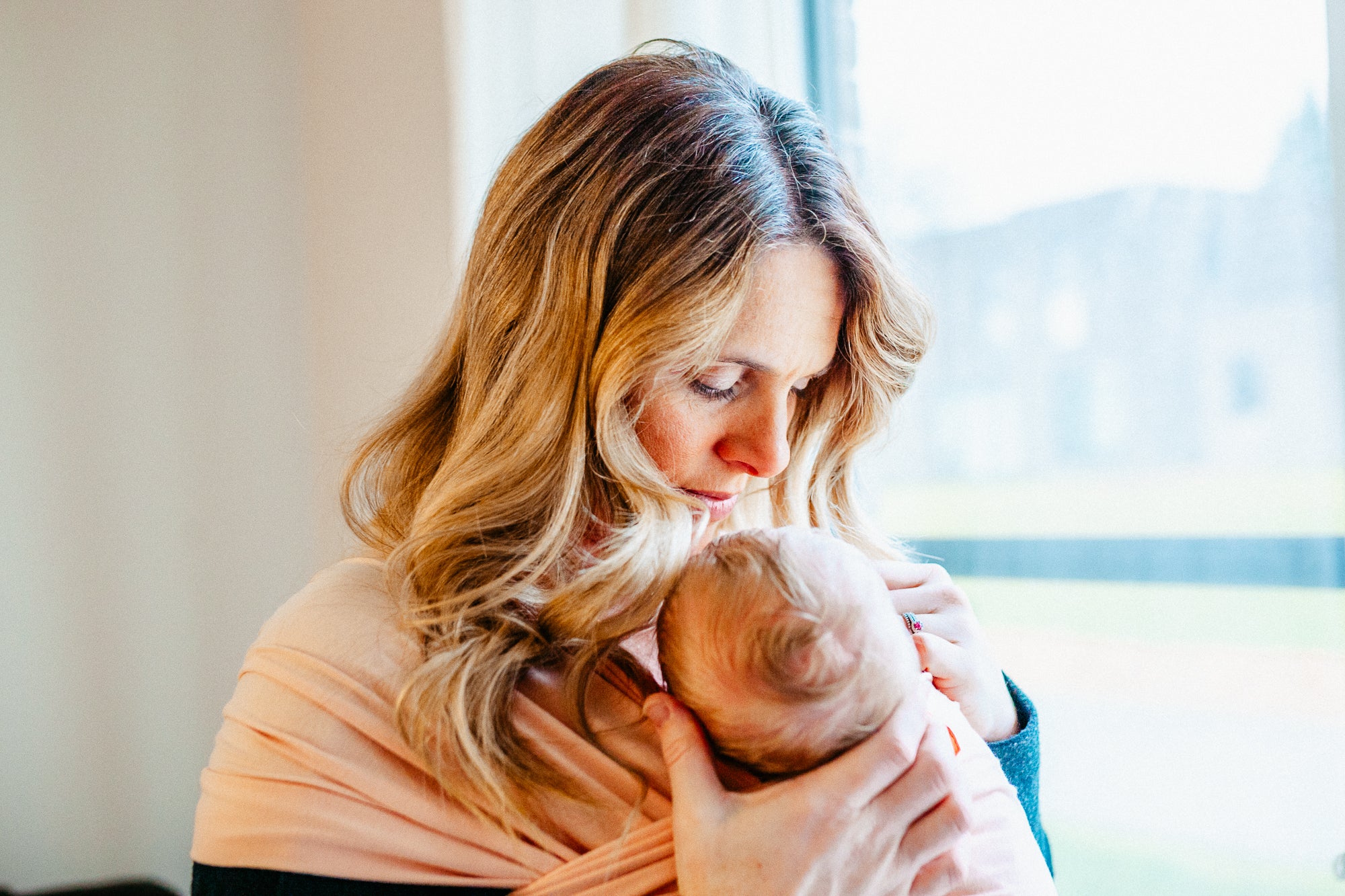 Peaceful moment of babywearing near me as a mom cradles her infant in an organic pink baby wrap.