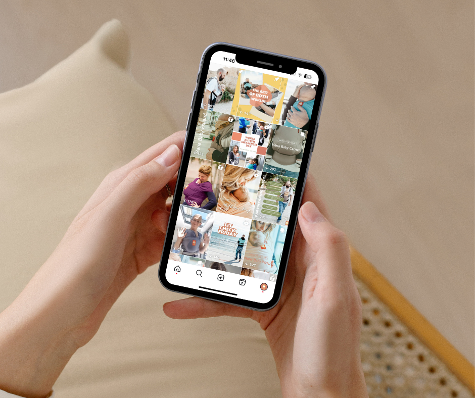 A person holds a smart phone in both hands against a blurred on beige background. On the smartphone is the instagram feed of the brand Hana Baby who is on the look out for Babywearing Mum Influencers.